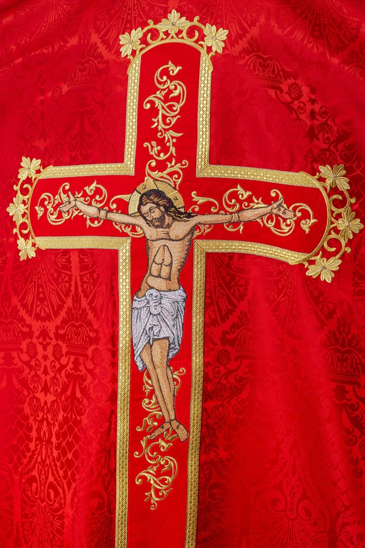 Red embroidered chasuble close-up of Jesus Christ on the gold cross