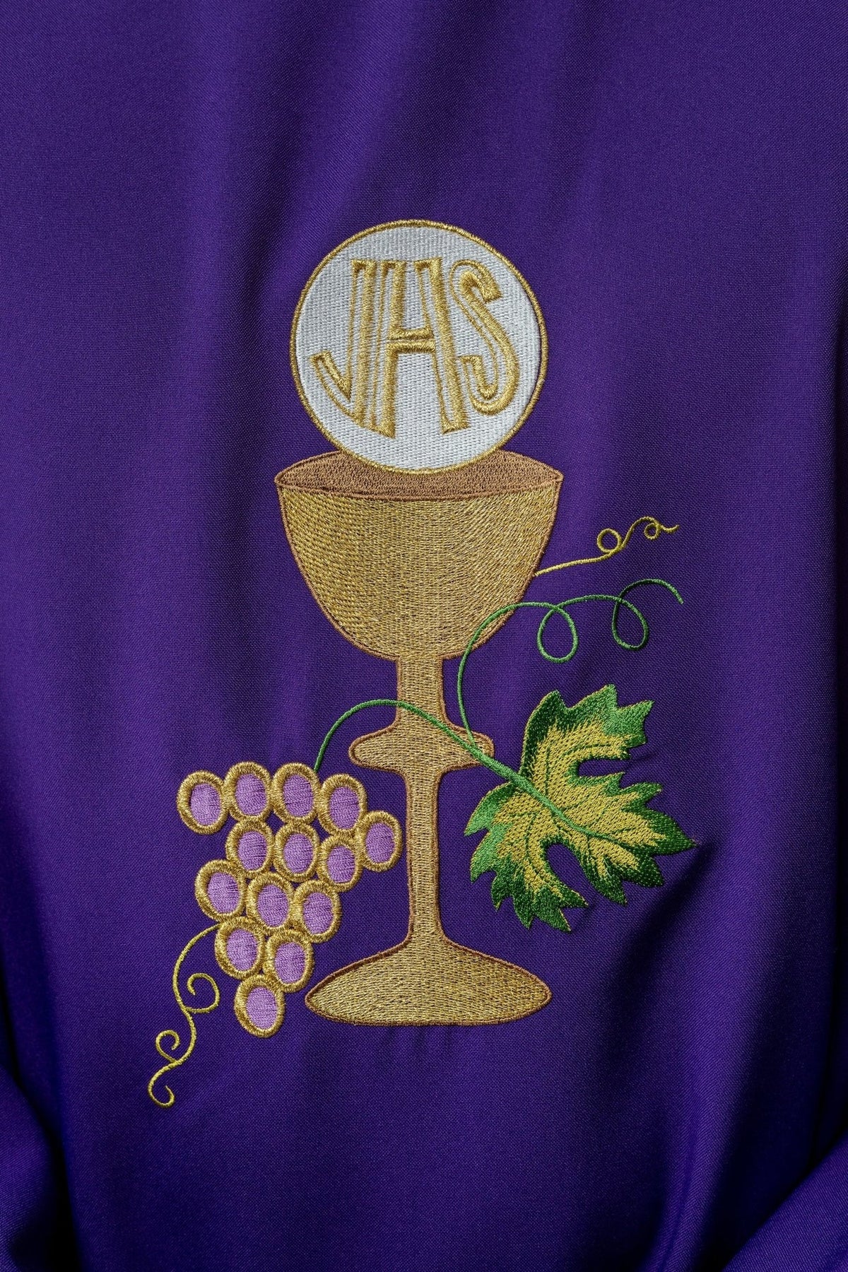 Purple chasuble embroidery close-up showing gold chalice and grapes