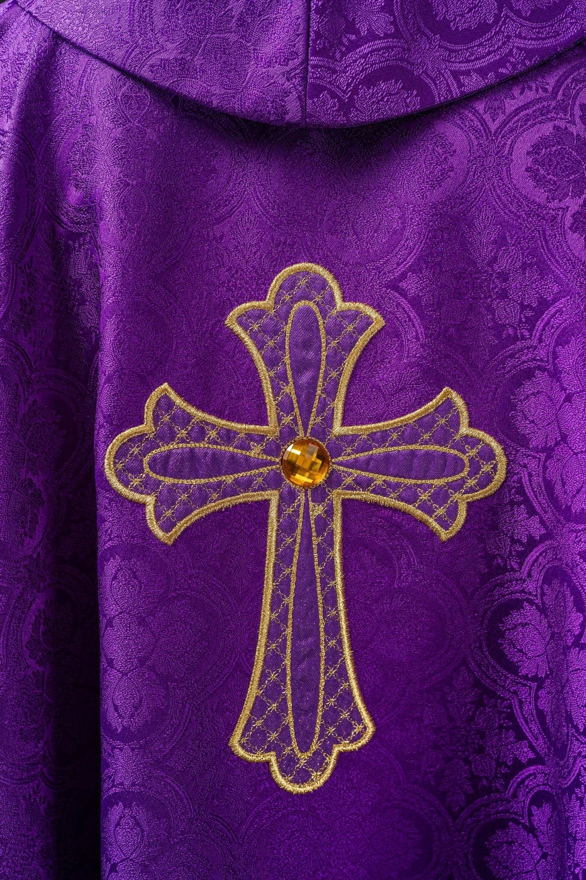 Purple chasuble close-up of gold cross embroidery with jeweled center