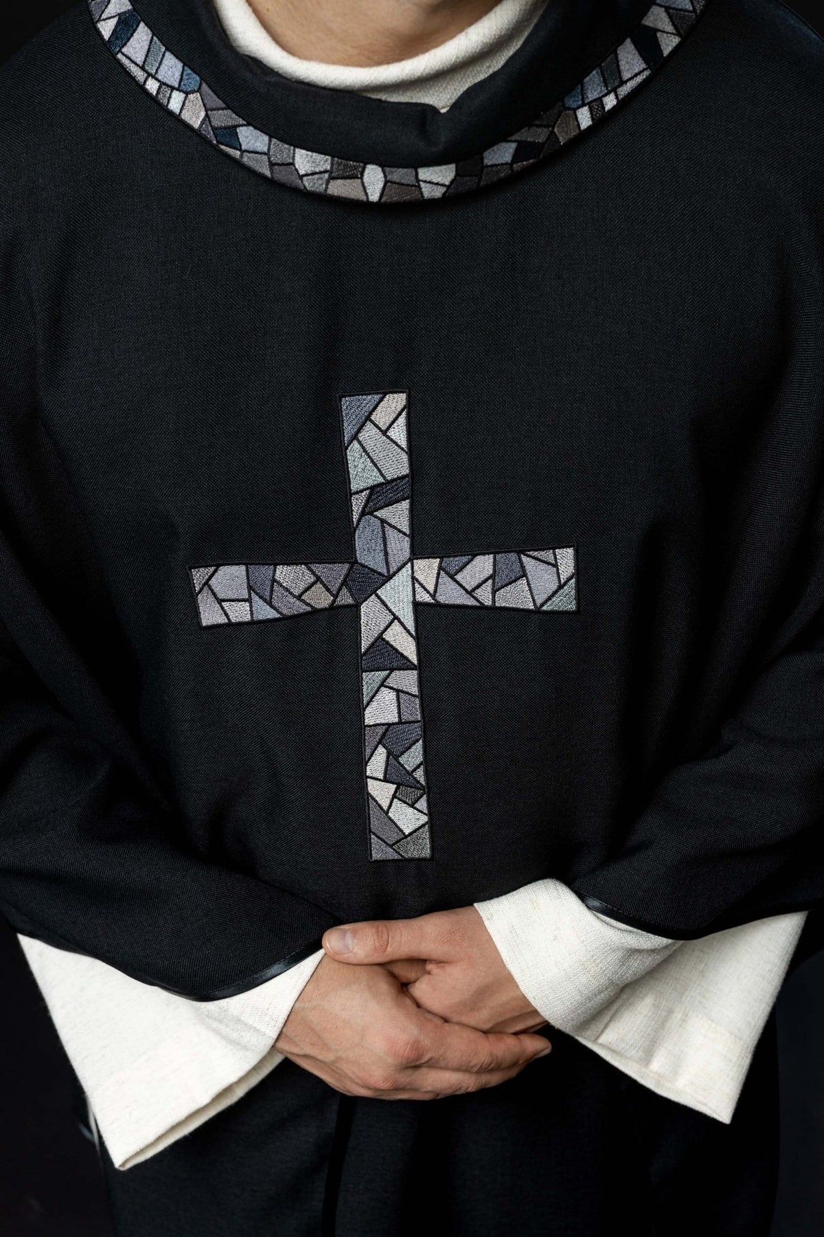 Black chasuble close-up showing mosaic cross and stand-up collar trim