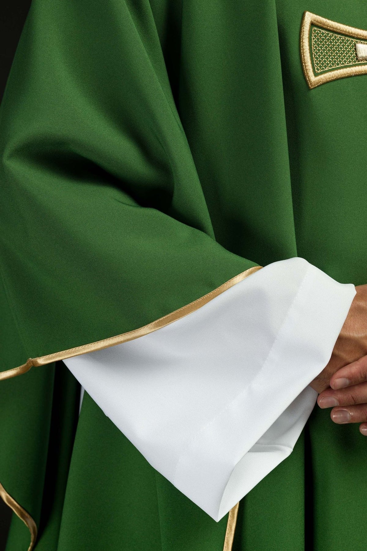 Green chasuble close-up showing gold trim and white sleeve