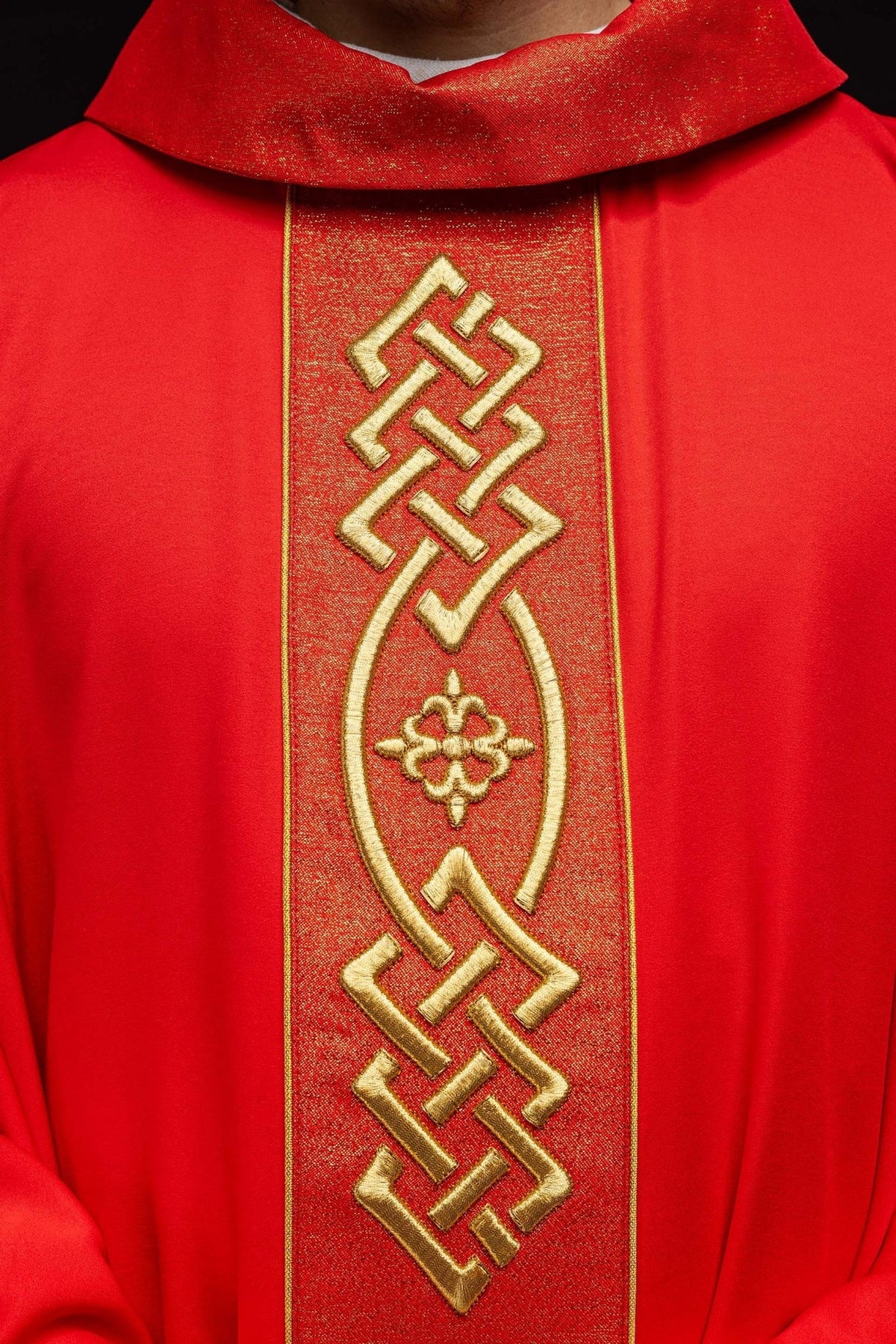 Red chasuble close-up showing gold embroidery on the central satin panel