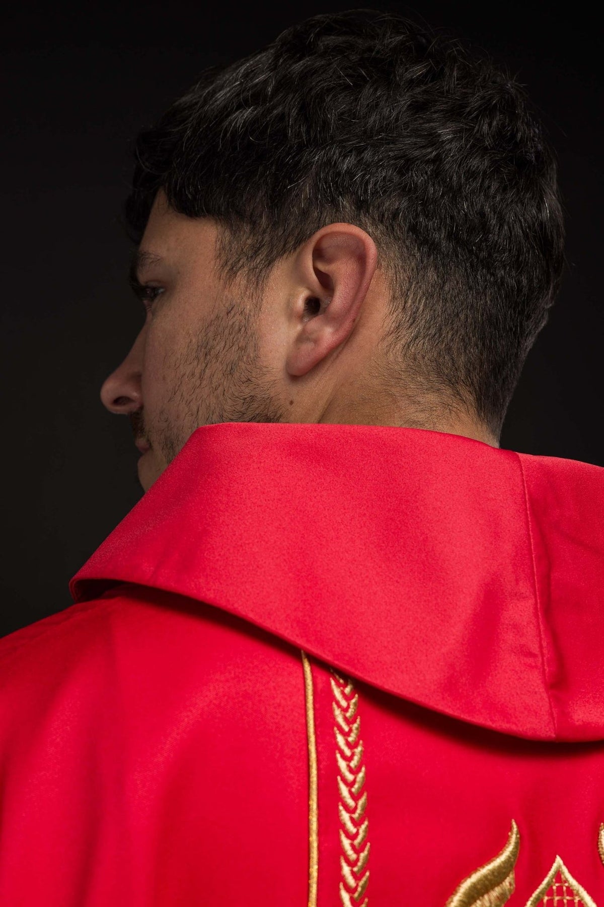 Red chasuble side view showing satin fabric, gold trim and embroidered orphrey