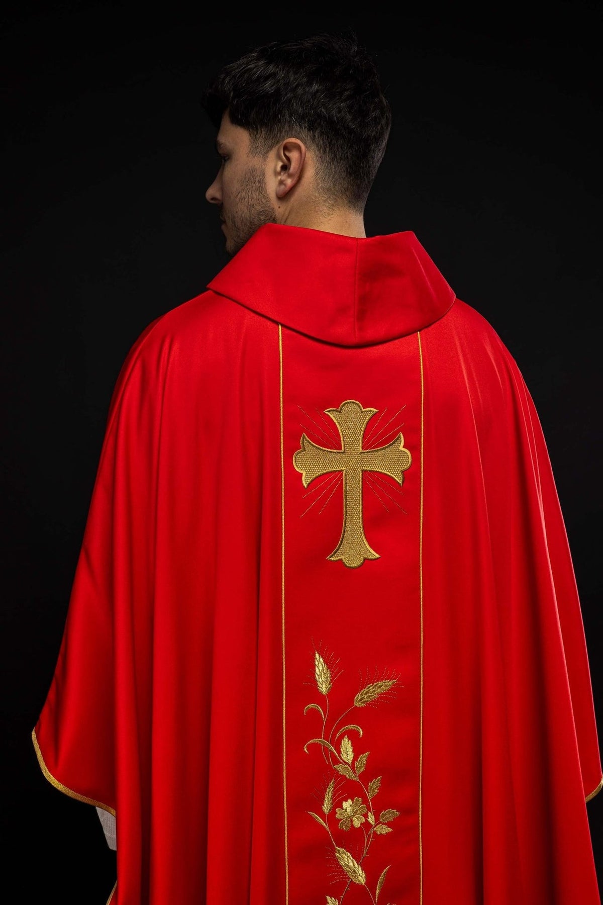 Red chasuble sleeve detail with small embroidered cross and gold trim