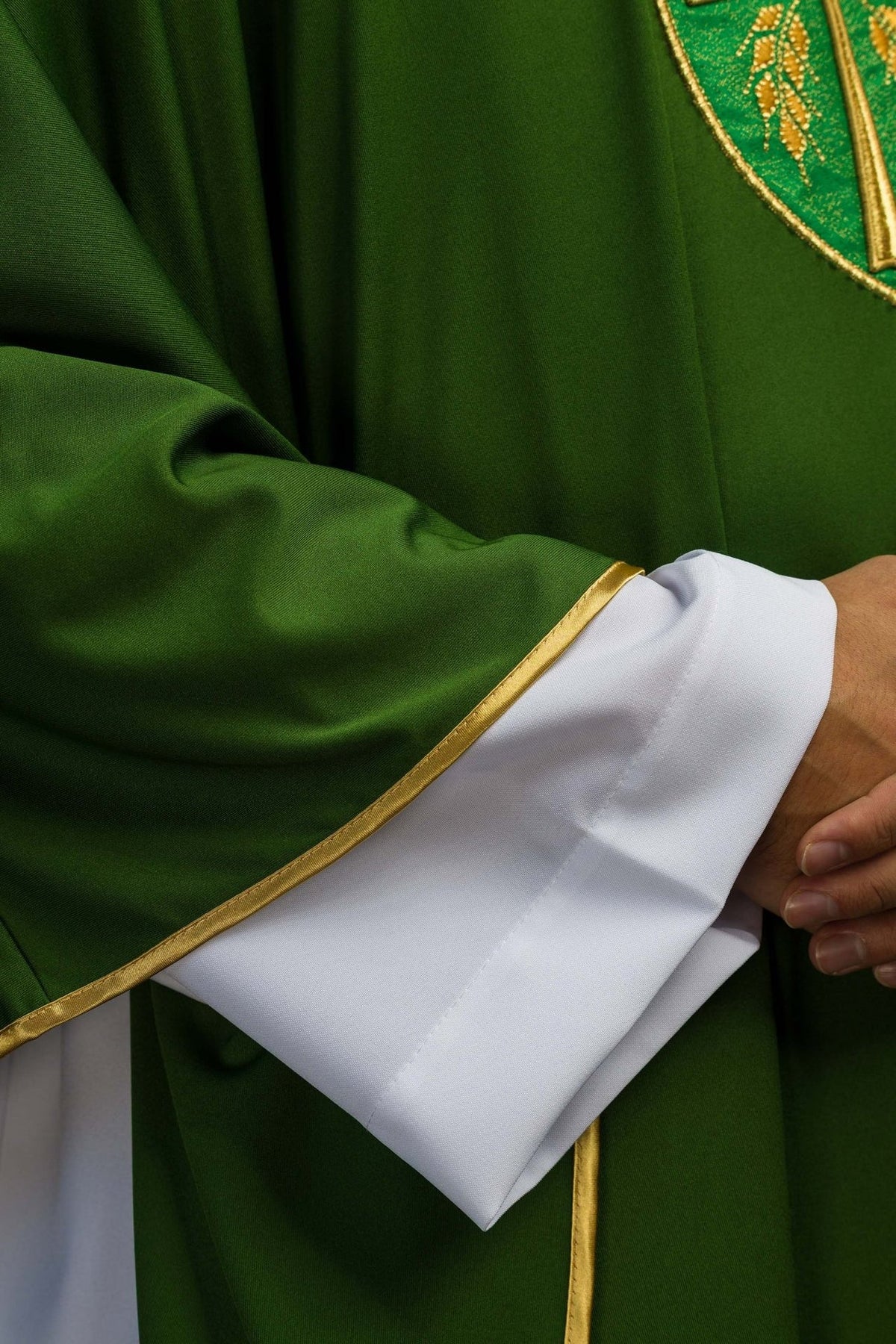 Green chasuble sleeve close-up with gold trim and white cuff visible