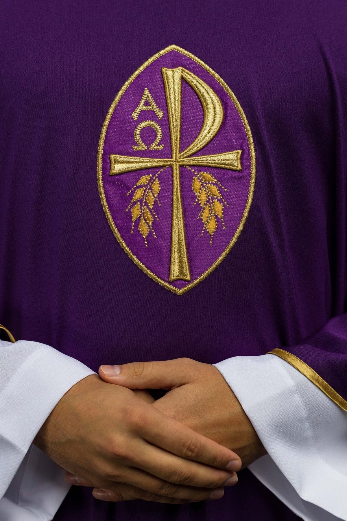 Purple chasuble close-up showing gold embroidered cross and wheat motifs