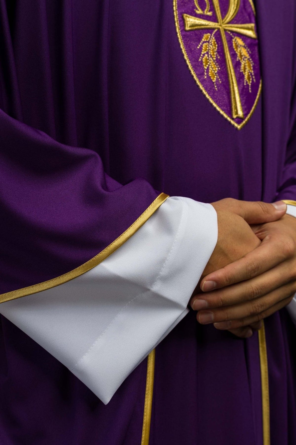 Purple embroidered chasuble close-up showing gold trim on the sleeve edge