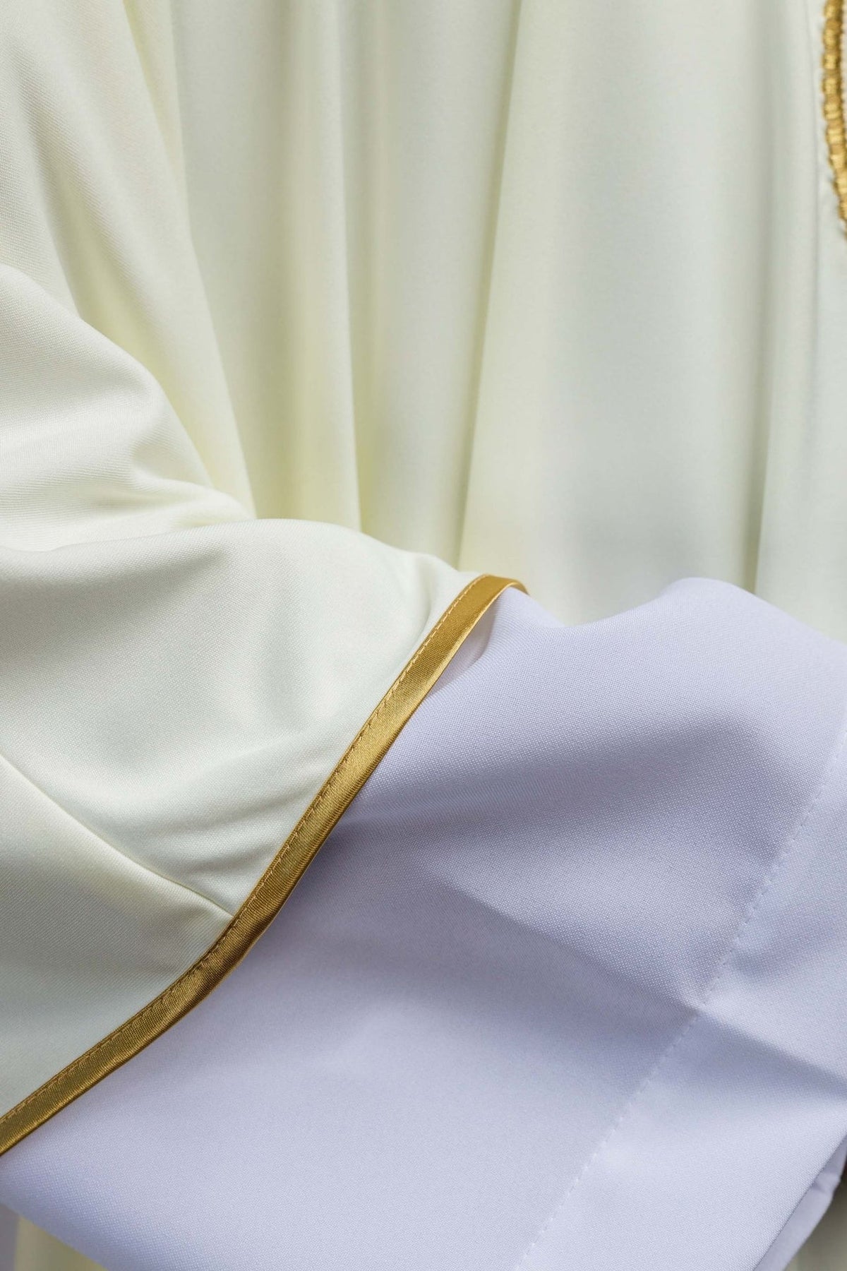 SACROLITE knit chasuble sleeve close-up showing gold trim and white alb cuff