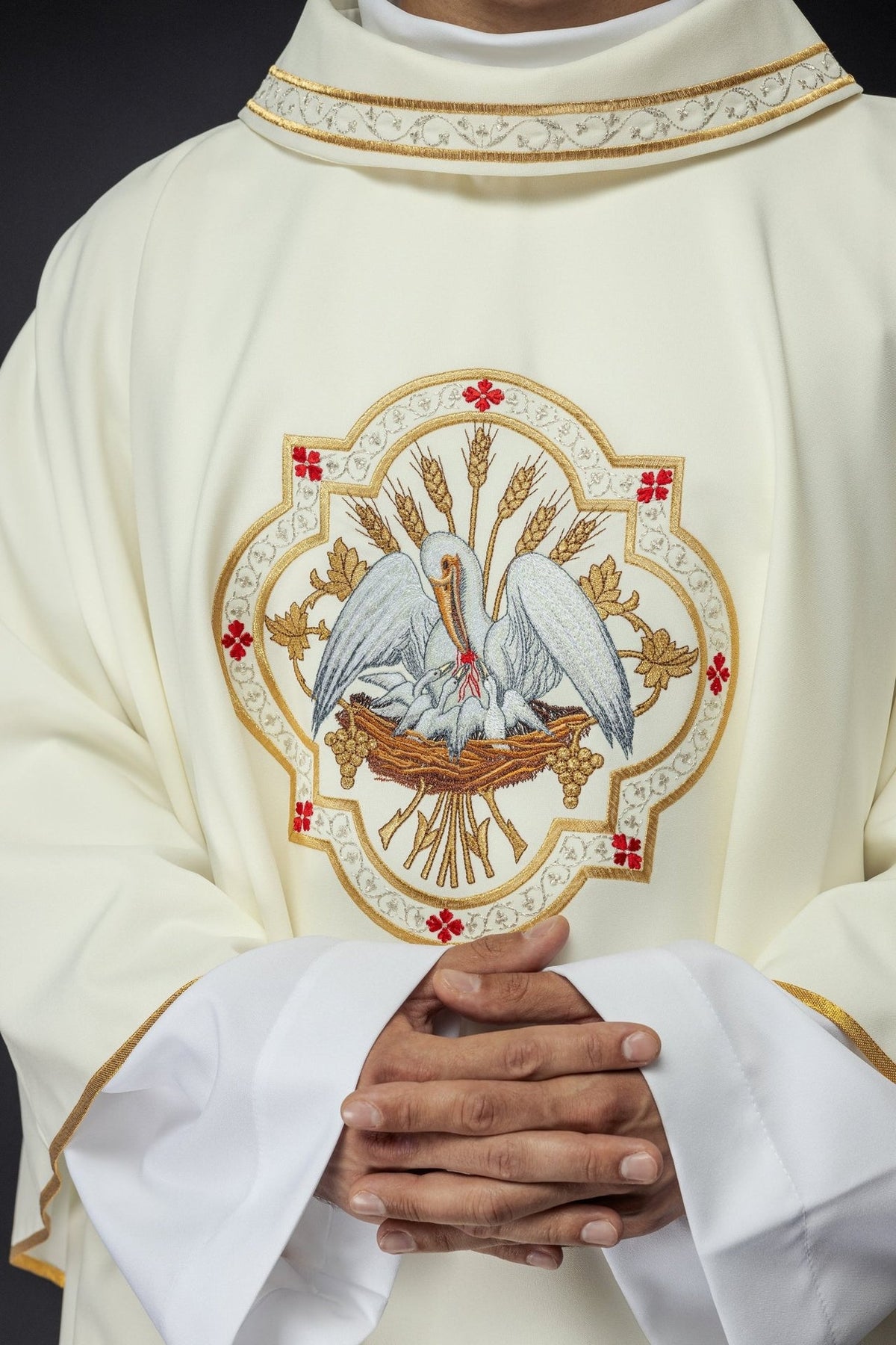Ecru chasuble close-up showing embroidered pelican motif and gold-trimmed collar