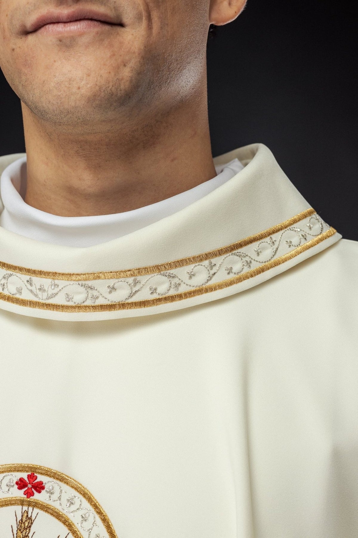 Ecru chasuble sleeve detail with gold trim and white cuff visible