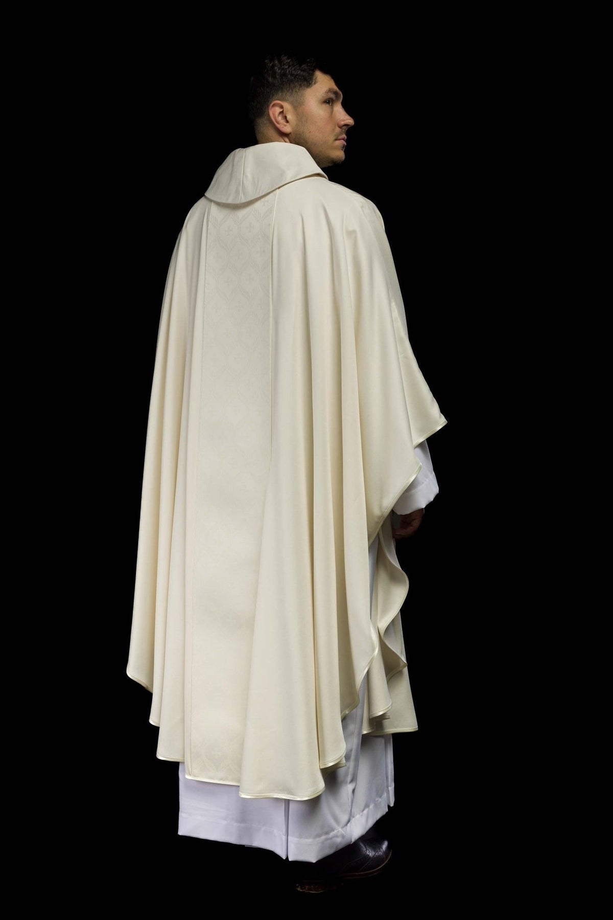 Ecru chasuble side-back view showing flowing fabric and orphrey