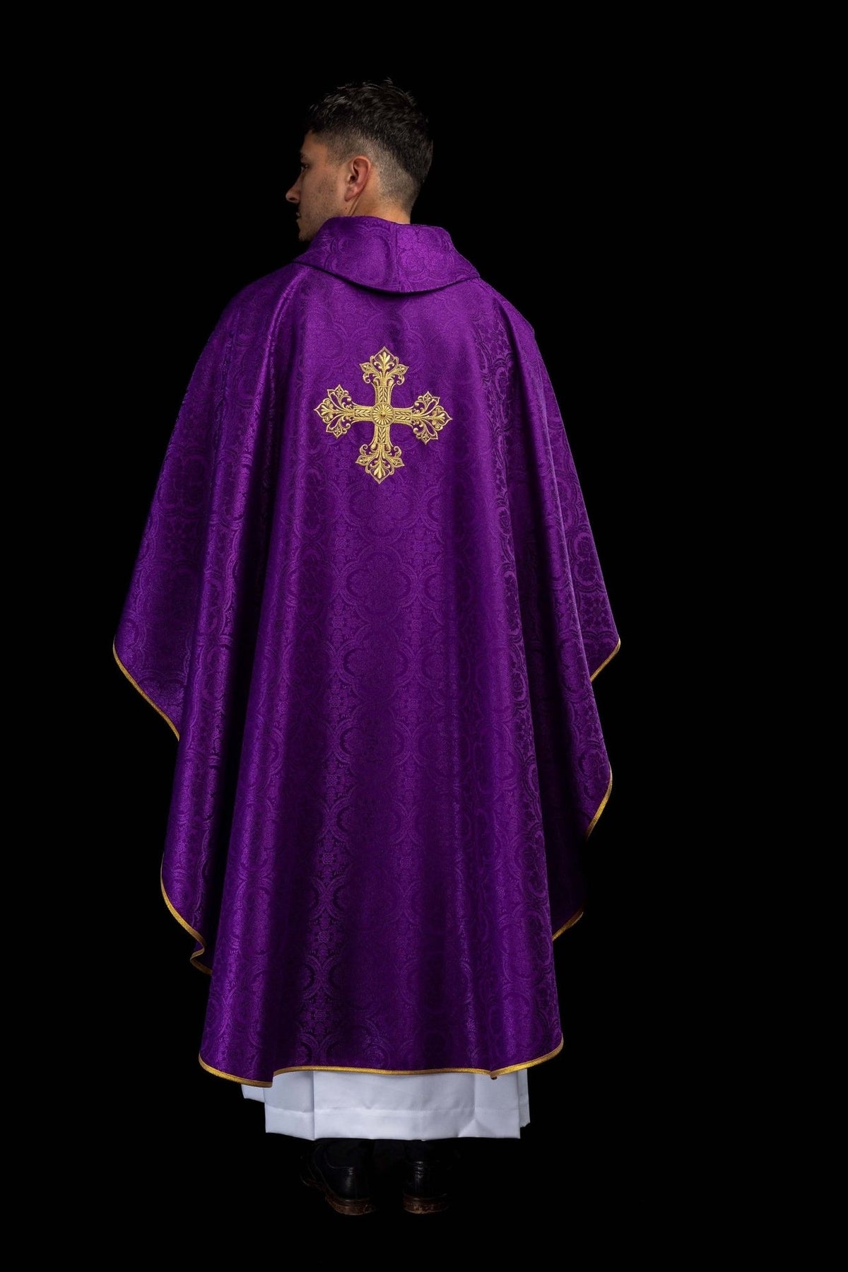 Purple chasuble worn angled front view with gold cross embroidery and flowing gold trim