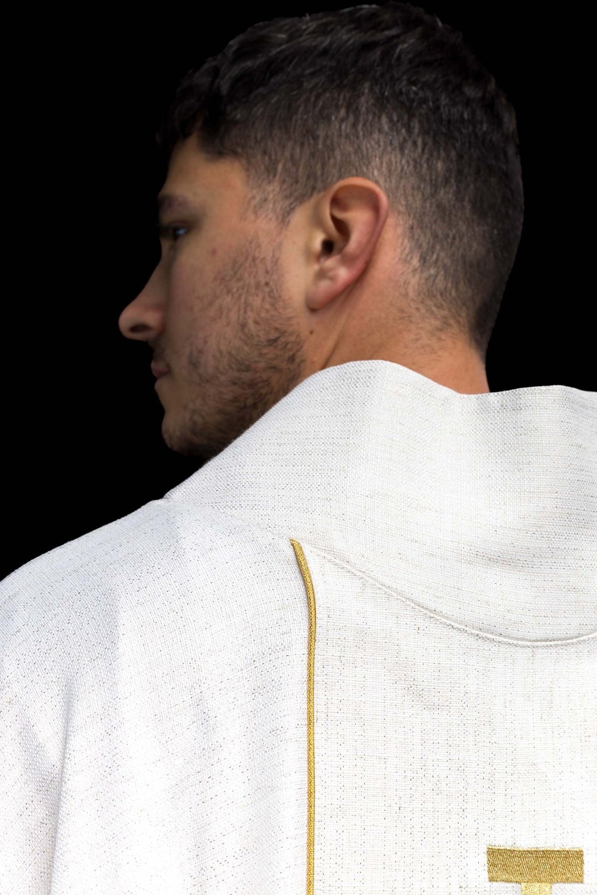Side view of ecru chasuble showing gold trim and collar