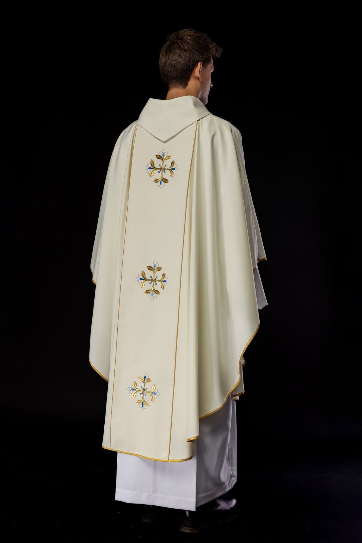 Catholic chasuble back view with three blue-and-gold embroidered motifs and gold-trimmed ivory fabric