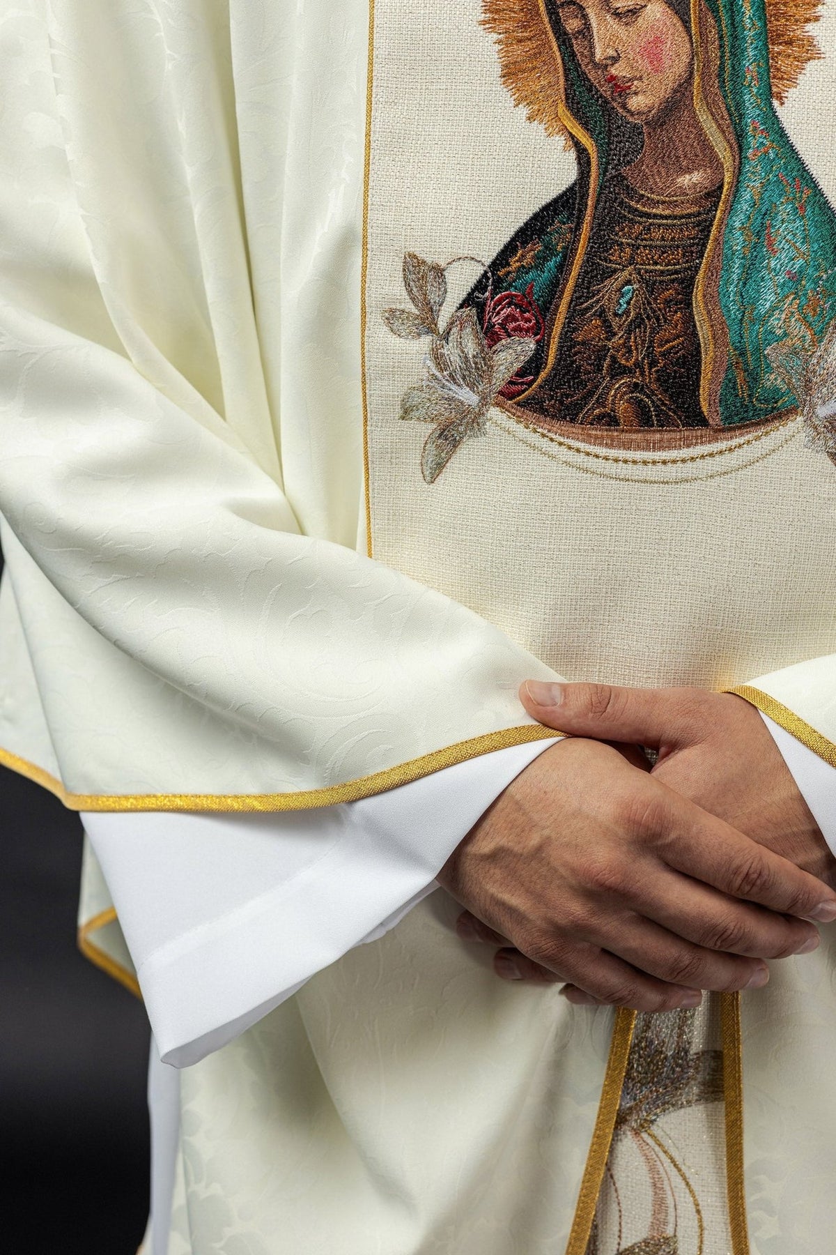 Chasuble detail showing white satin fabric, floral embroidery and gold trim