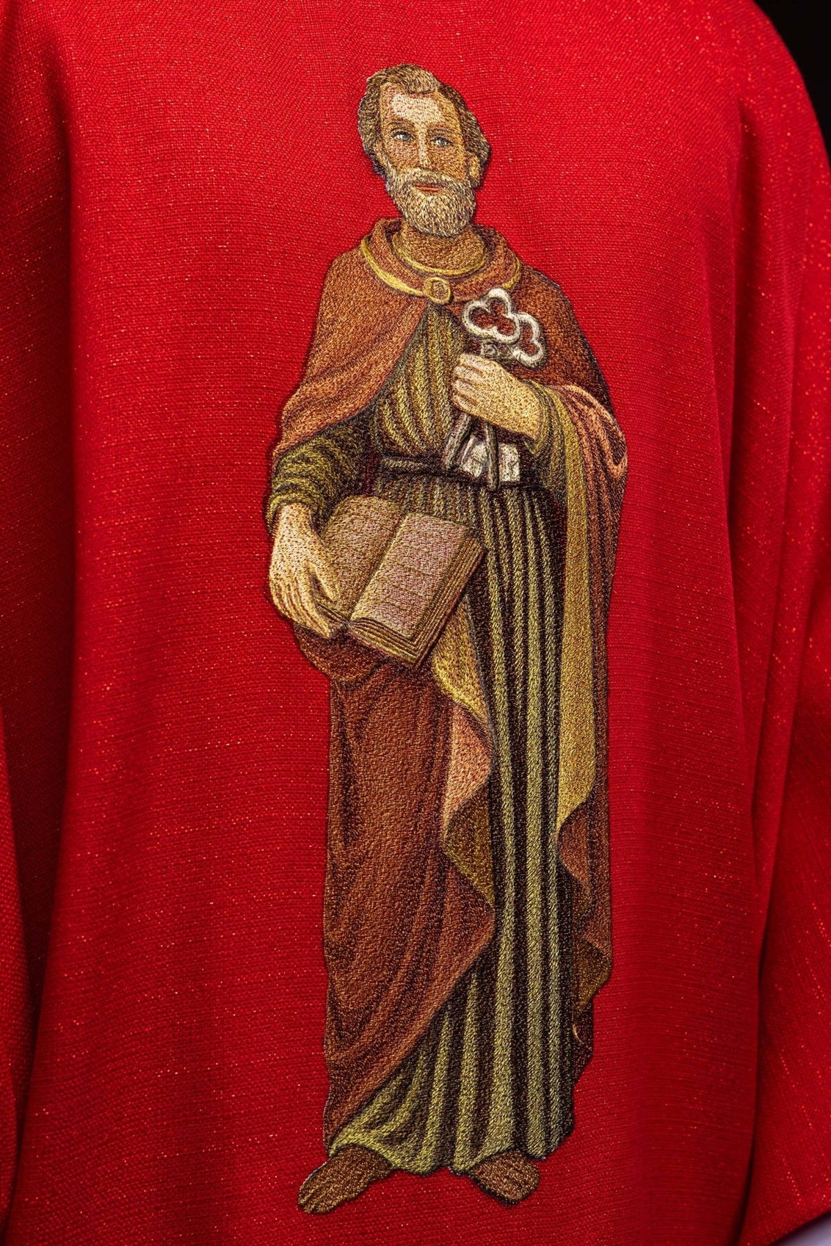 Red chasuble close-up showing embroidered Saint Peter holding keys and a book