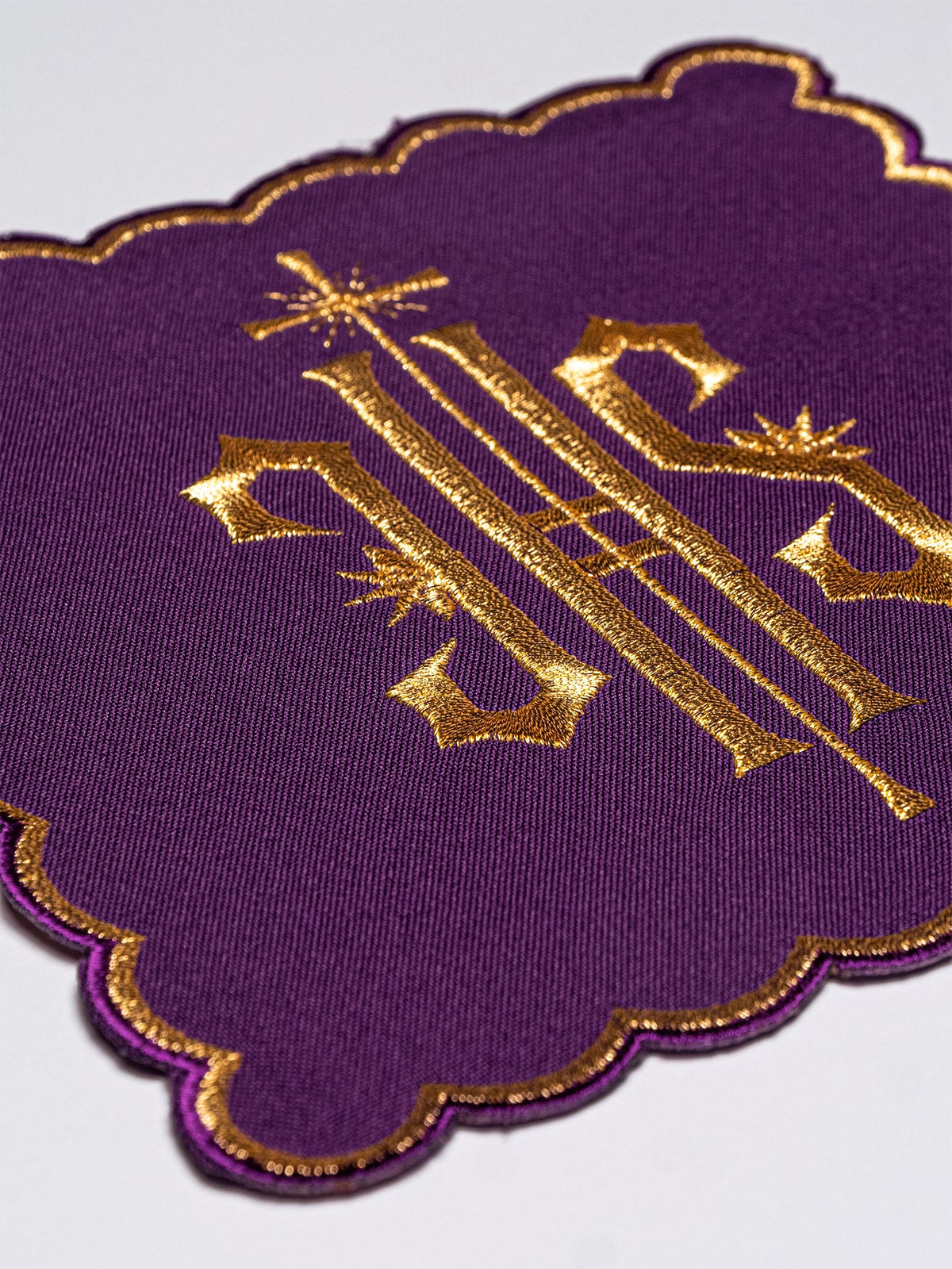 Purple chalice pall with gold embroidered IHS symbol and scalloped gold edging