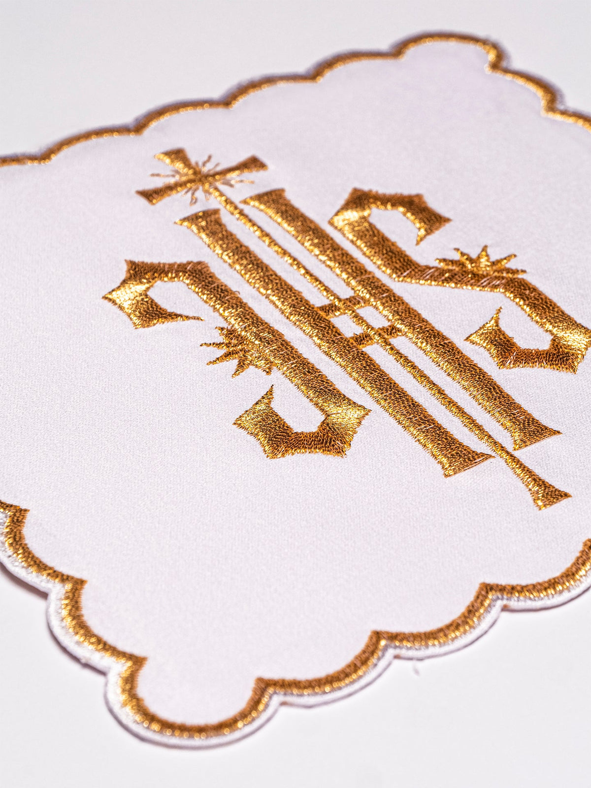 White chalice pall with gold embroidered IHS symbol and scalloped gold edging
