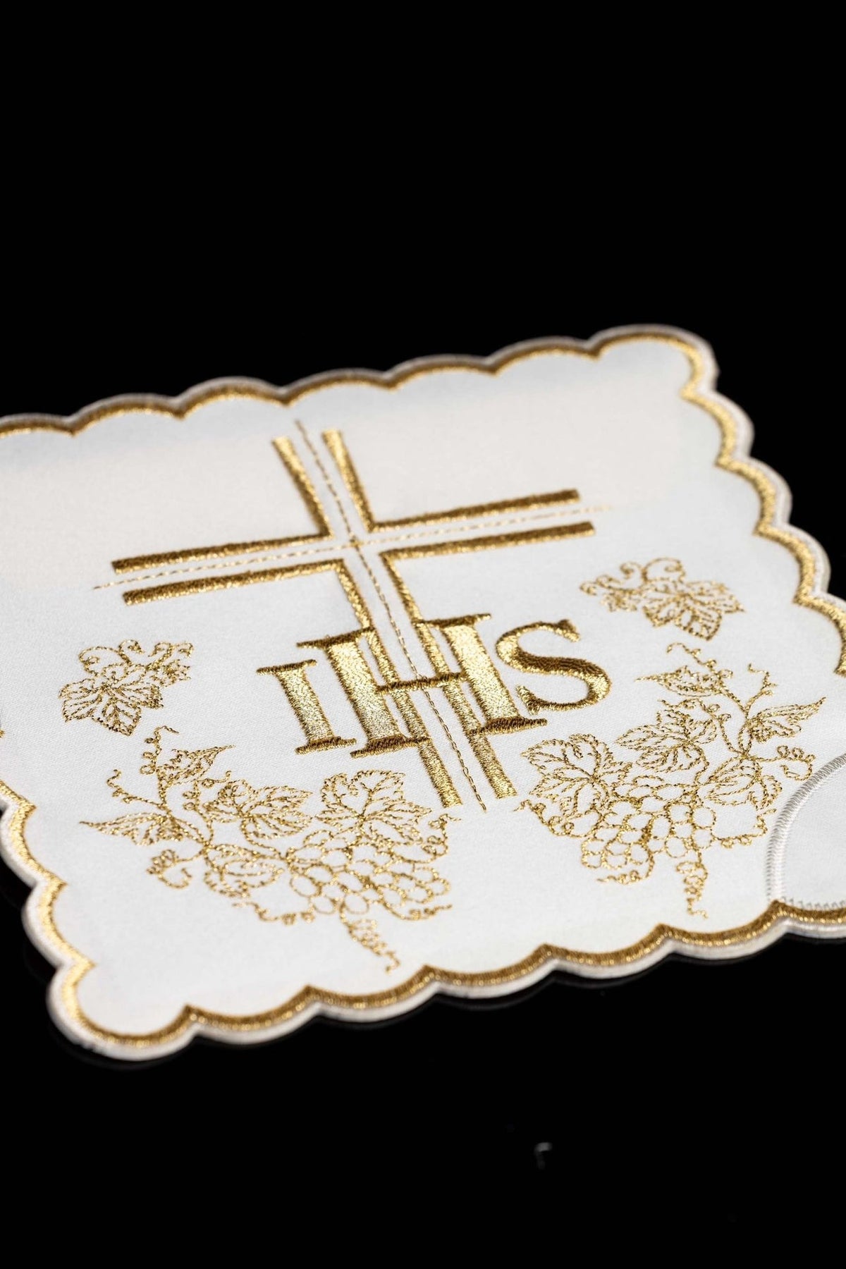 White chalice pall close-up with gold IHS, cross and grape embroidery