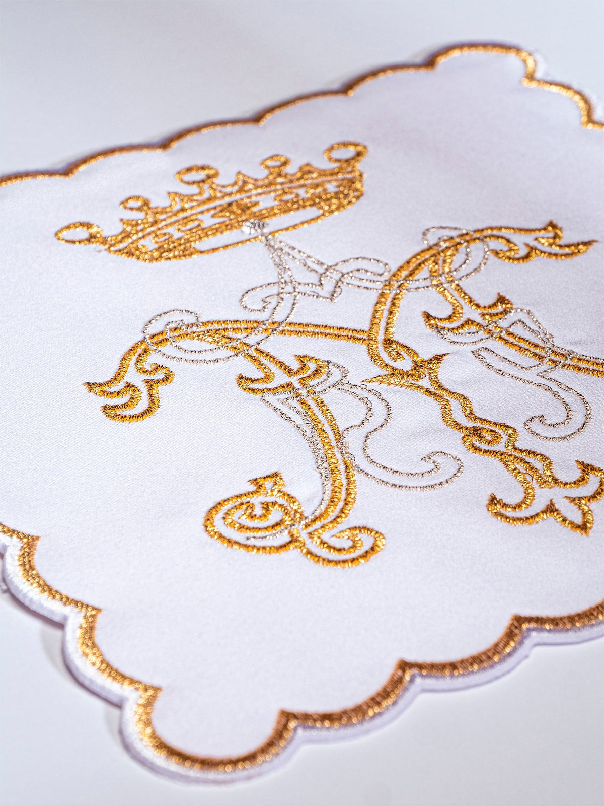 Chalice pall close-up showing gold embroidered Marian symbol and scalloped edge