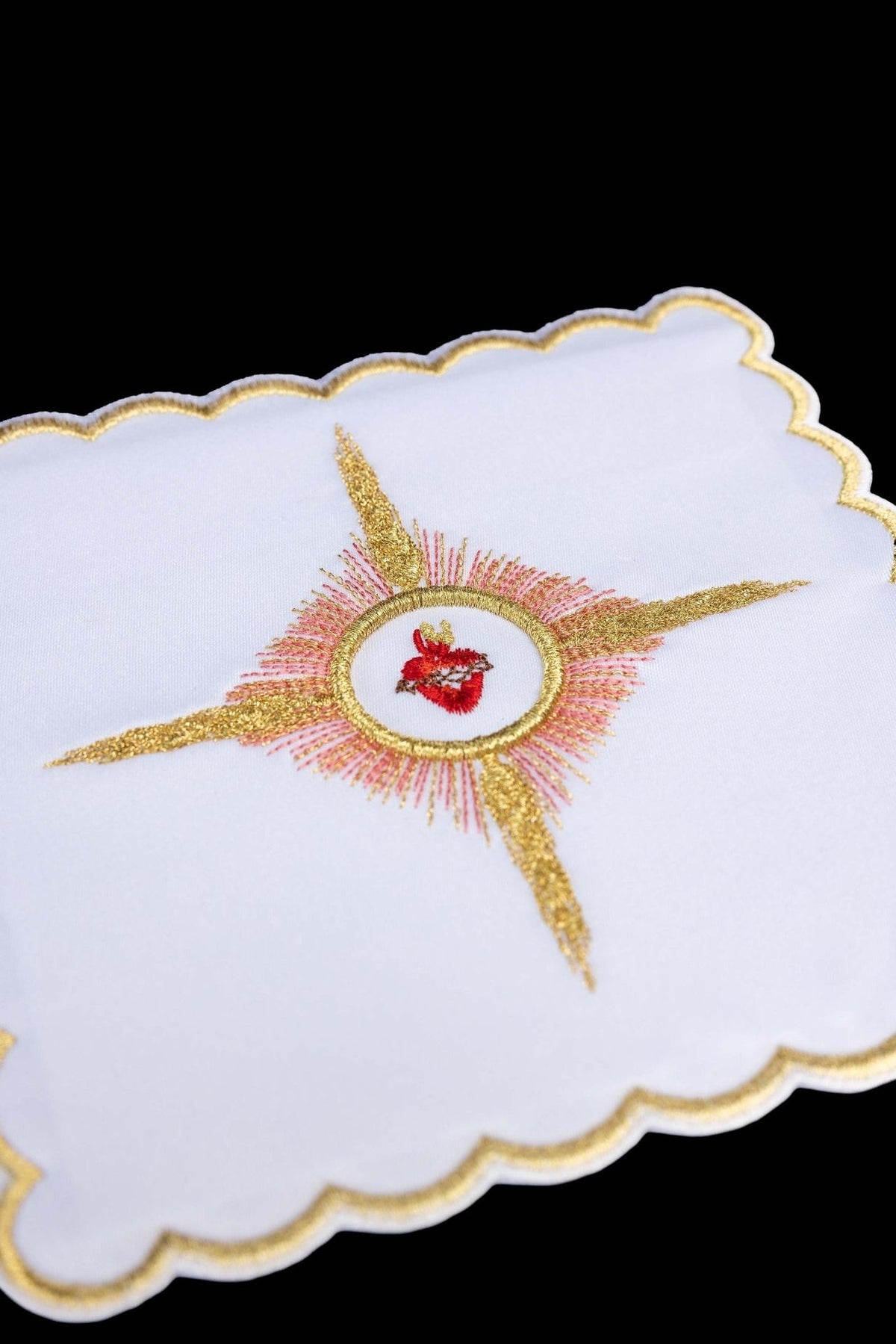 Chalice pall close-up showing embroidered Sacred Heart of Jesus Symbol with gold and red rays