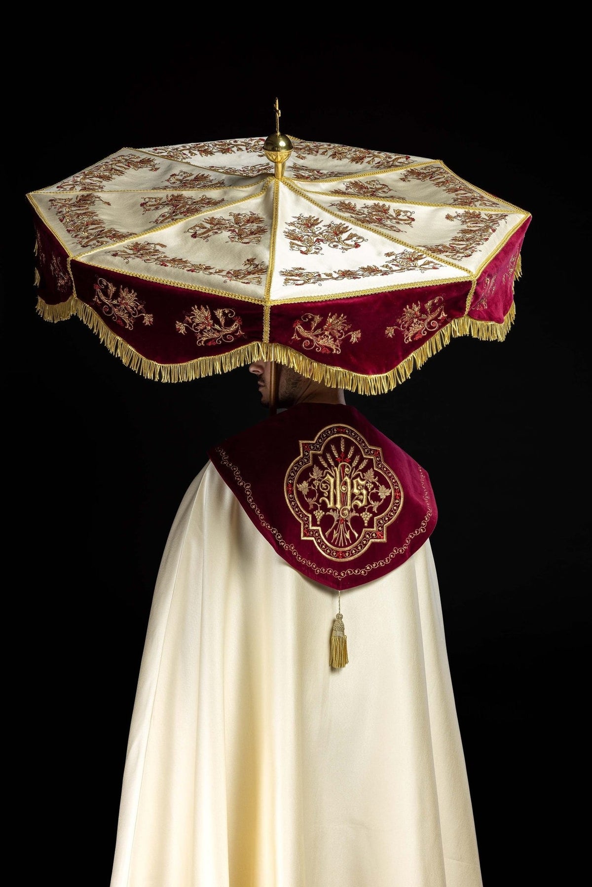 Processional umbrella worn from the back, showing embroidered burgundy valance and ecru panels