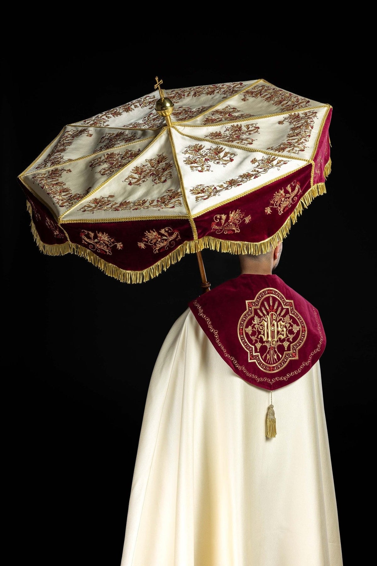 Processional umbrella worn, showing ecru panels, burgundy edge and gold embroidery