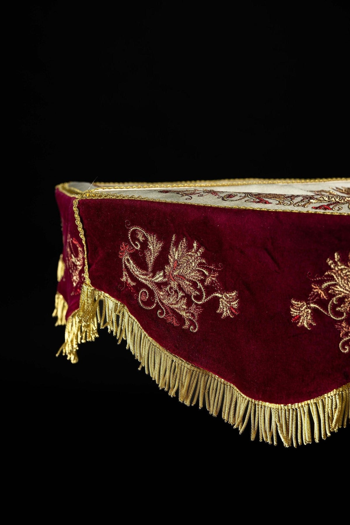 Processional umbrella detail showing burgundy valance with gold floral embroidery and fringe