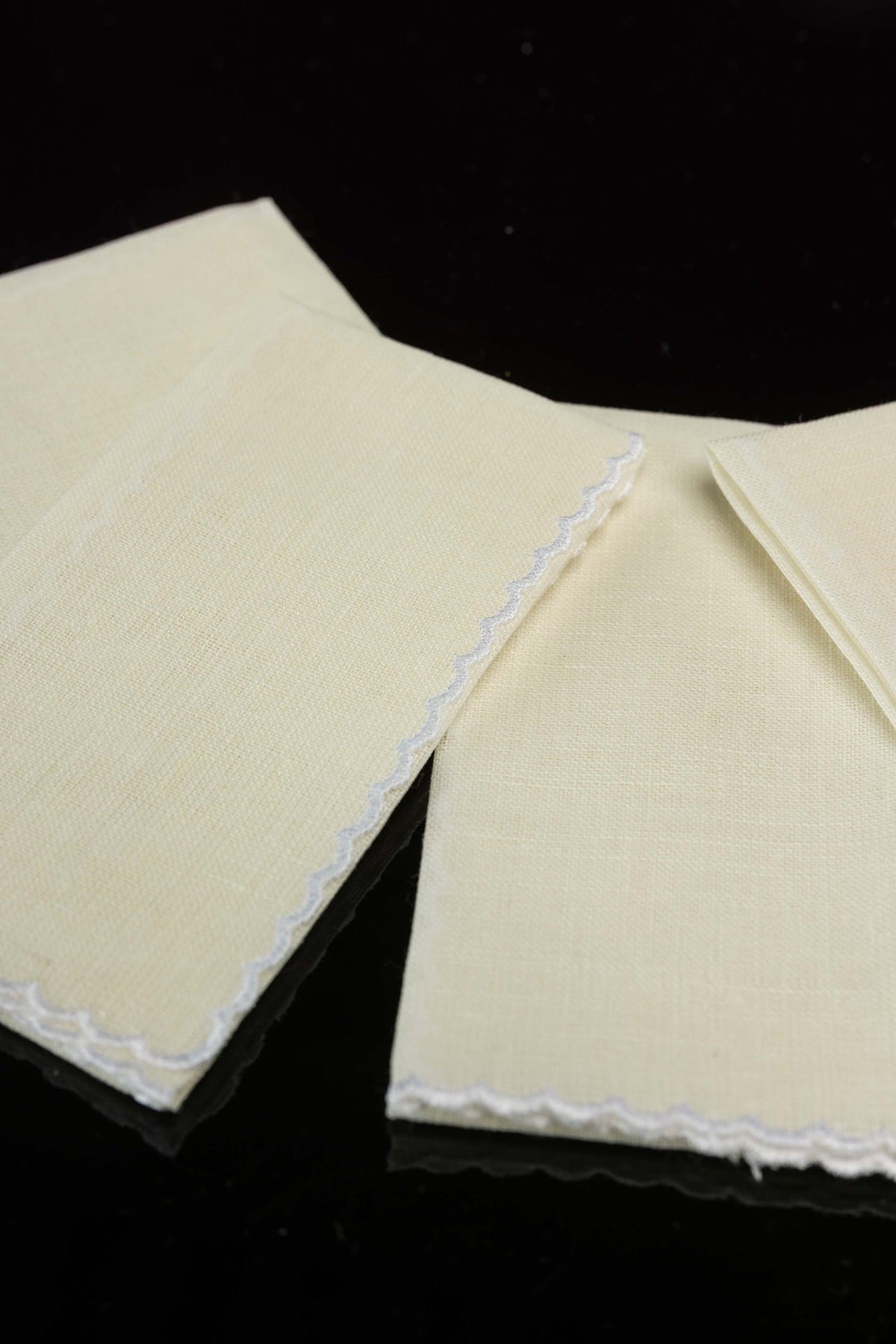 Linen lavabo towels close-up showing cream fabric and white scalloped edging
