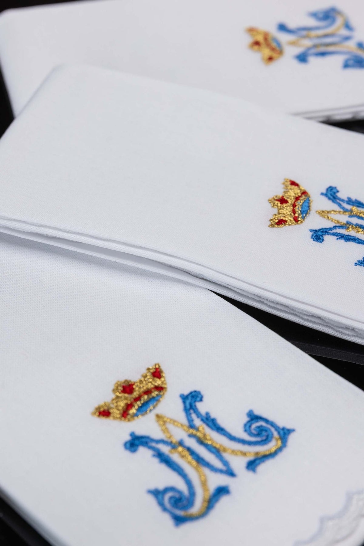 White purificators close-up showing layered cotton fabric and partial Marian embroidery