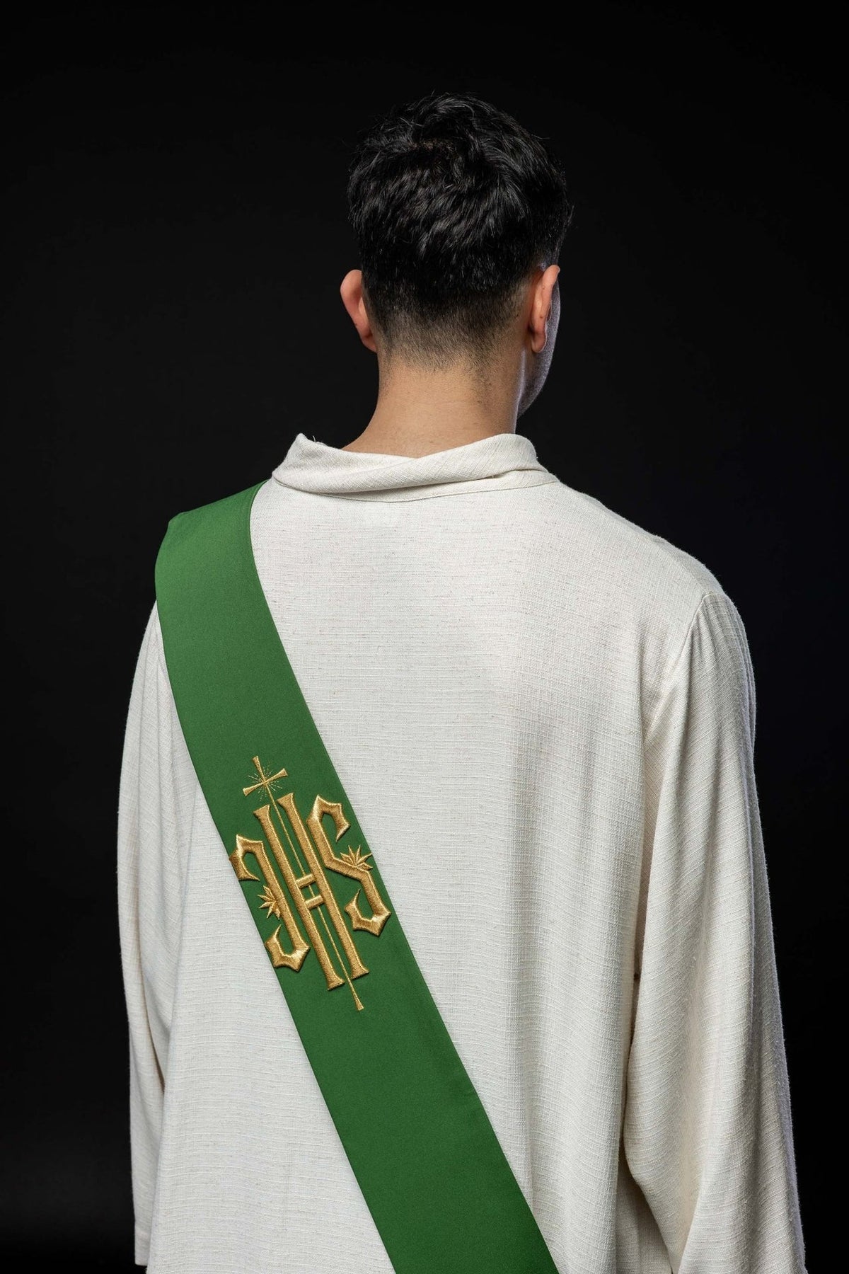 Green stole back view worn over a white alb with gold IHS and cross embroidery