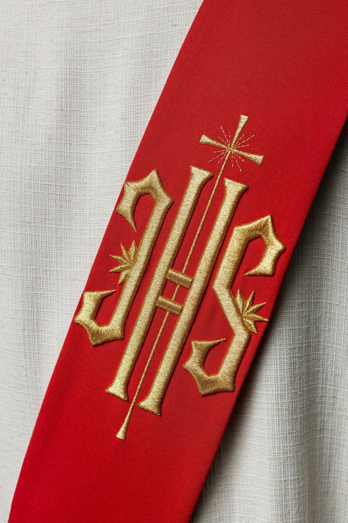 Red stole close-up showing gold embroidered IHS and cross