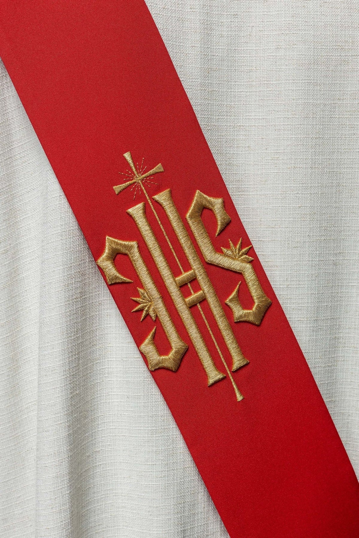 Red stole close-up showing gold IHS embroidery and cross on the back