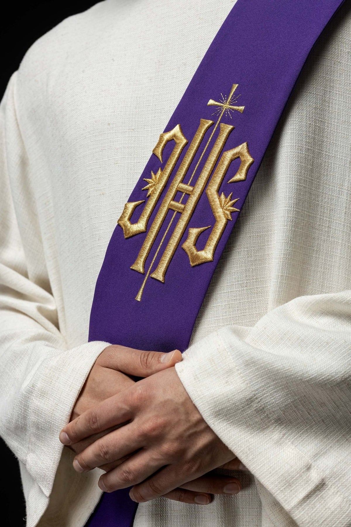 Purple stole close-up with gold embroidered IHS, cross and decorative rays