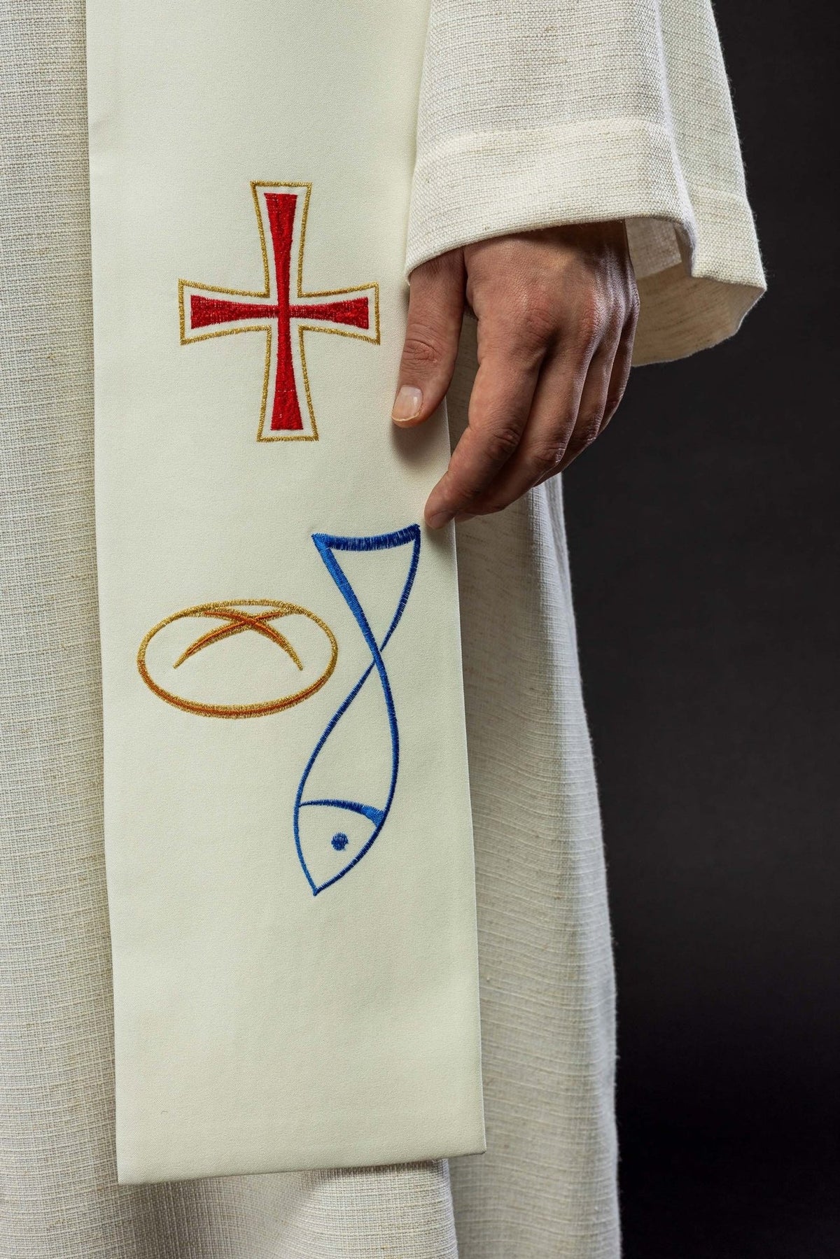 Embroidered ecru stole close-up with red cross, fish and bread motifs