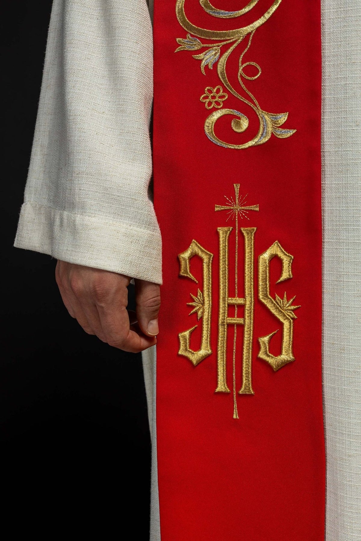Red priest stole close-up showing gold IHS embroidery and scrollwork