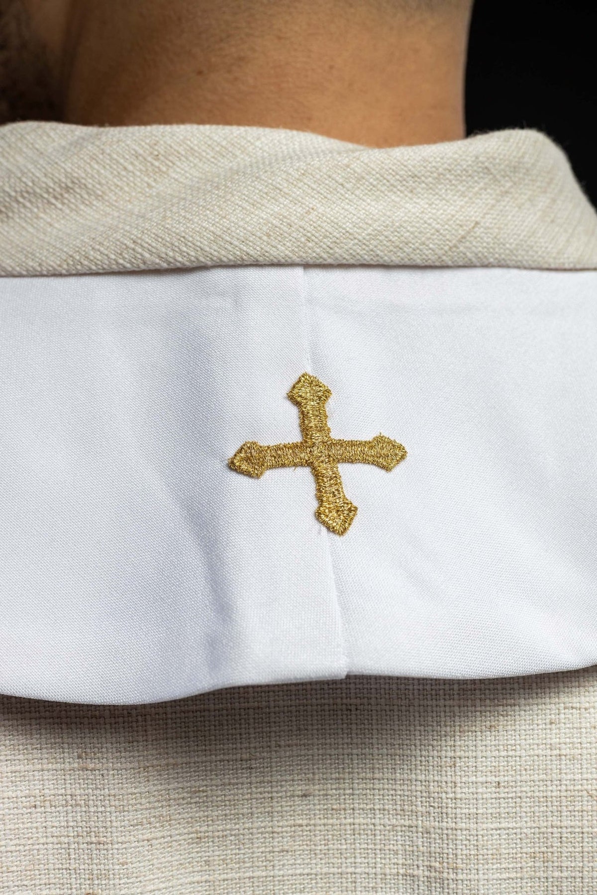 White stole detail showing gold embroidered cross at the neck