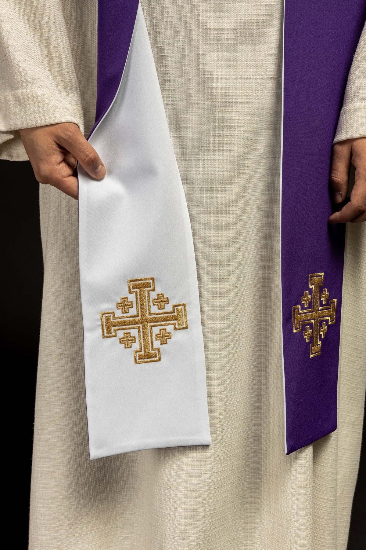Embroidered stole close-up showing white and purple sides with gold Jerusalem cross motifs