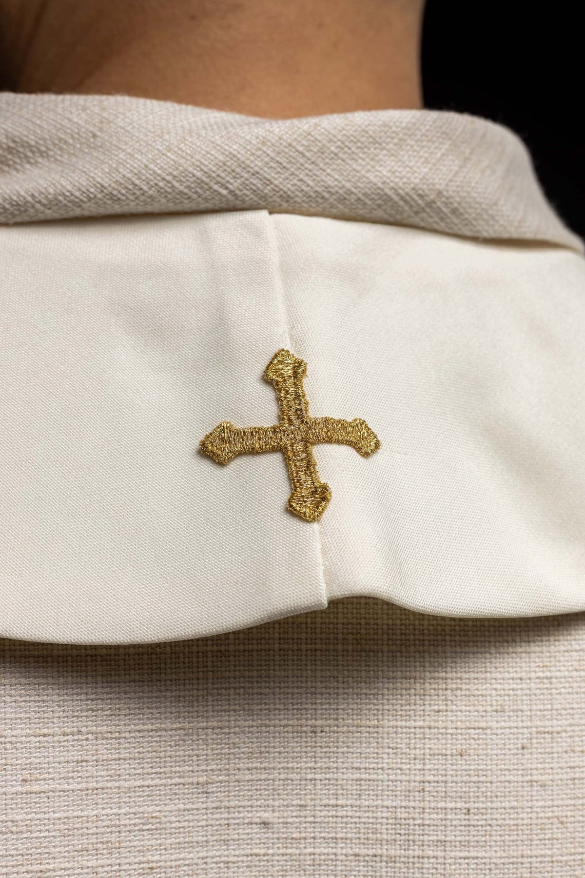 Ecru stole detail showing a gold embroidered cross and smooth fabric
