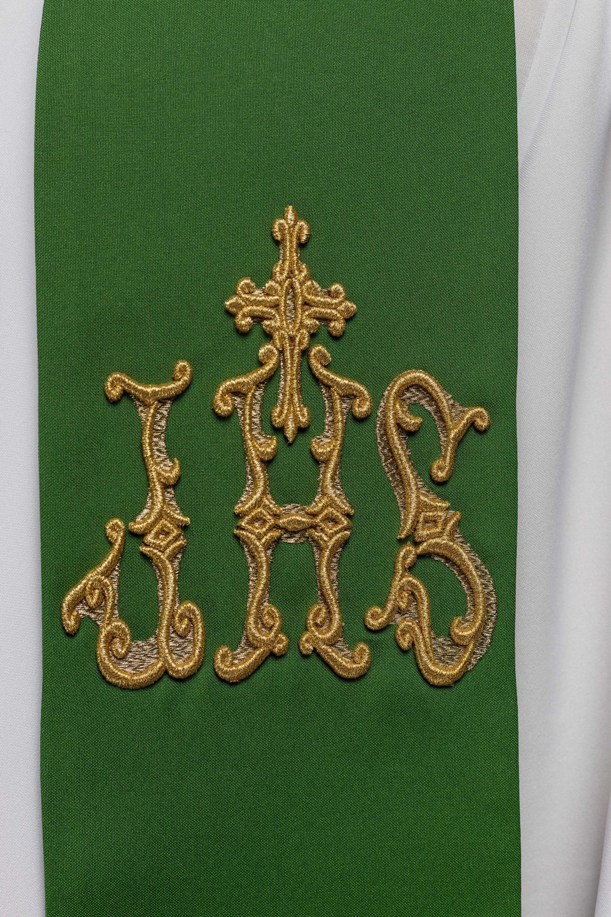 Green priest stole close-up showing embroidered gold cross and IHS