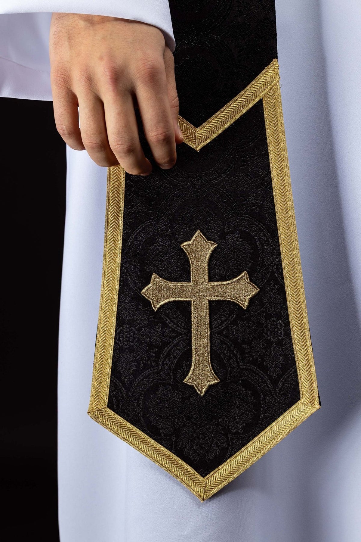 Black priest stole close-up with embroidered gold cross and gold trim