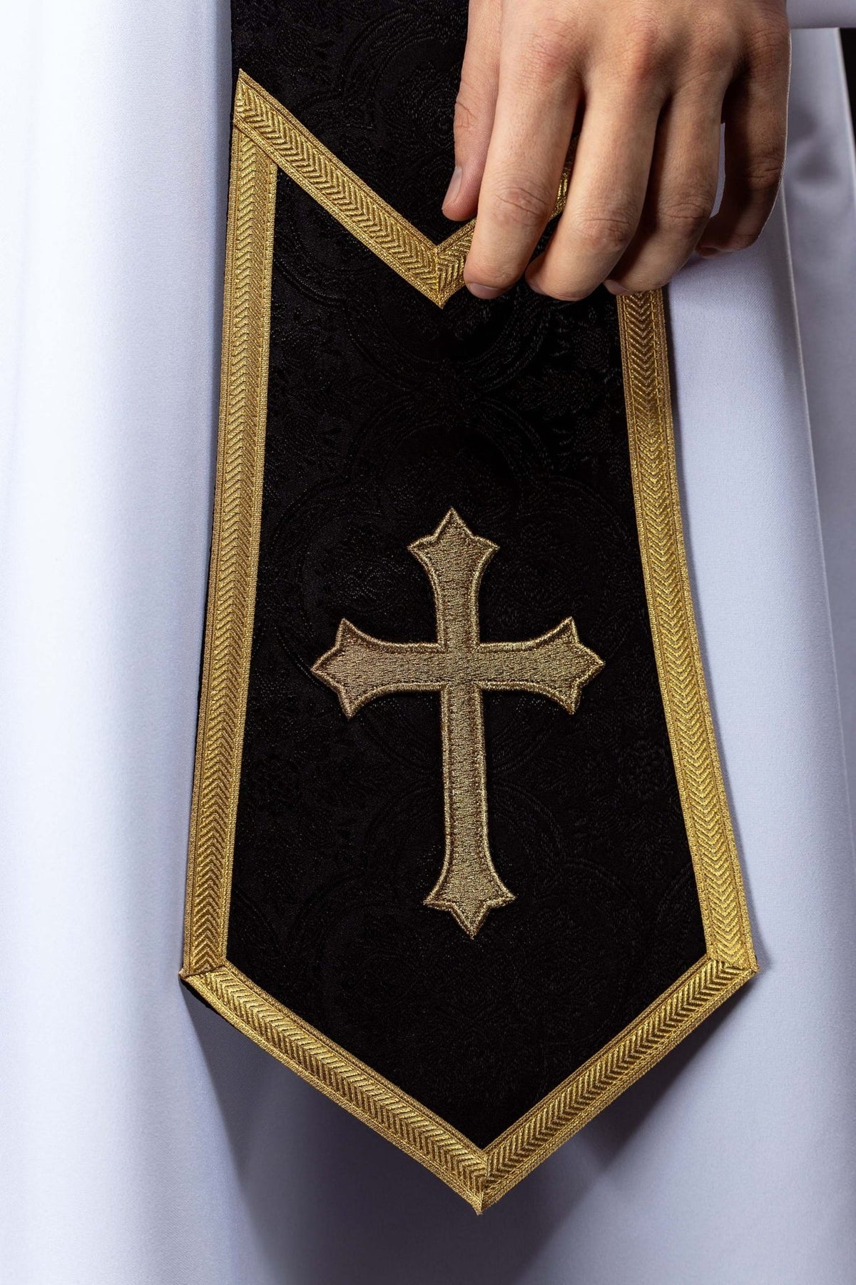 Black priest stole detail with embroidered gold cross and pointed end