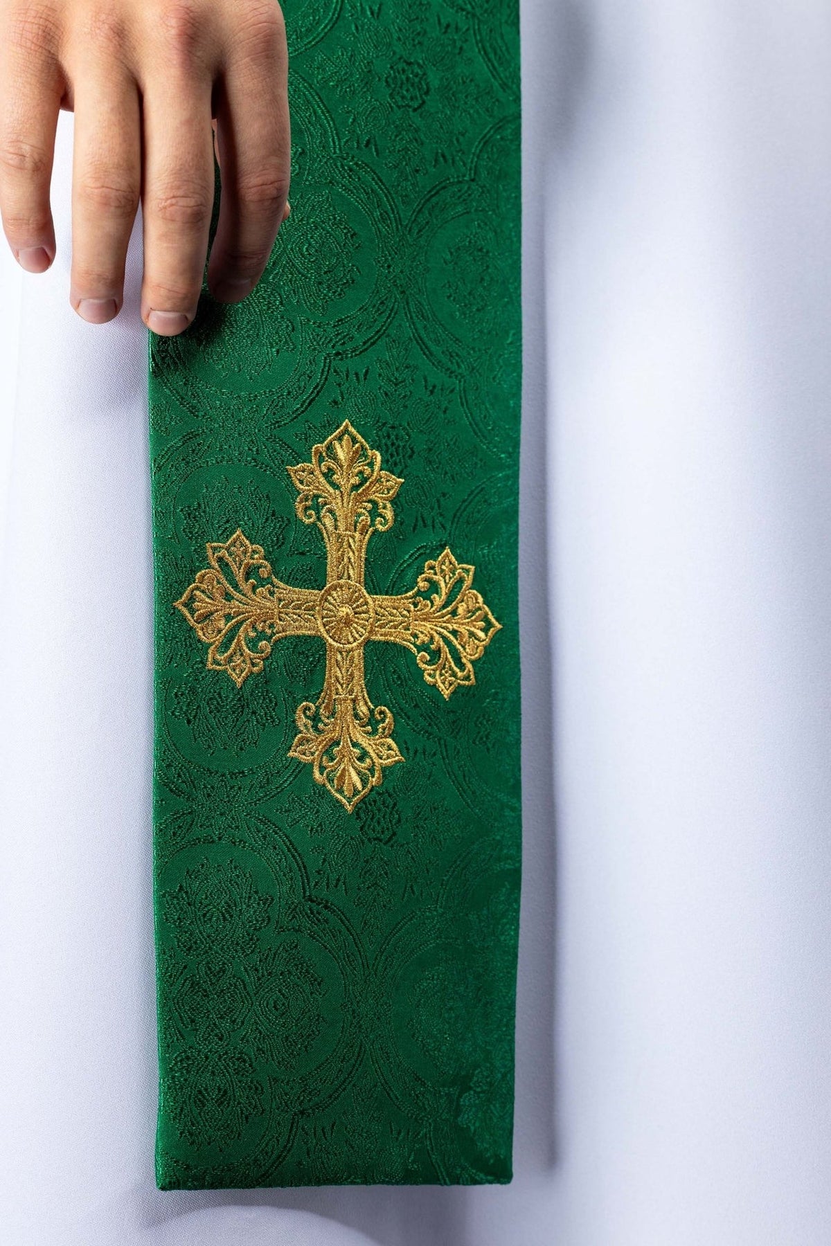 Green priest stole close-up with embroidered gold cross and patterned fabric