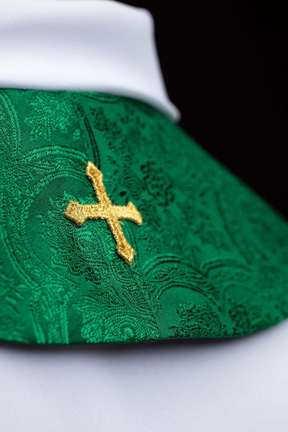 Green stole detail showing gold embroidered cross on jacquard fabric