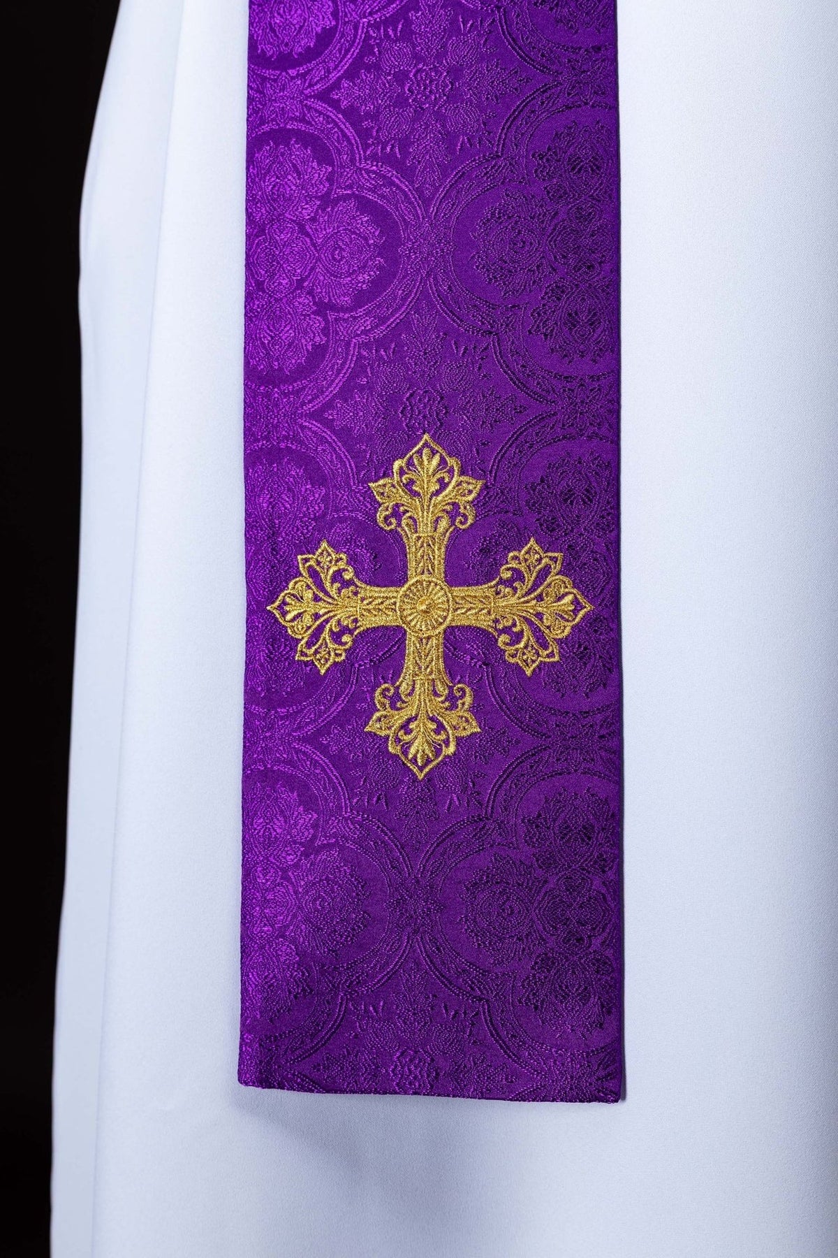 Purple stole close-up with embroidered gold cross and floral jacquard pattern