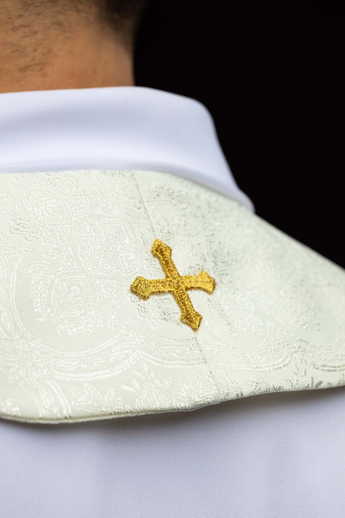 Ecru stole close-up showing a small embroidered gold cross