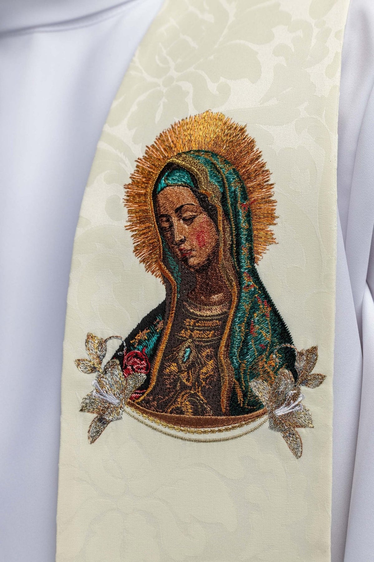 Stole close-up showing embroidered Our Lady and floral details on ecru fabric