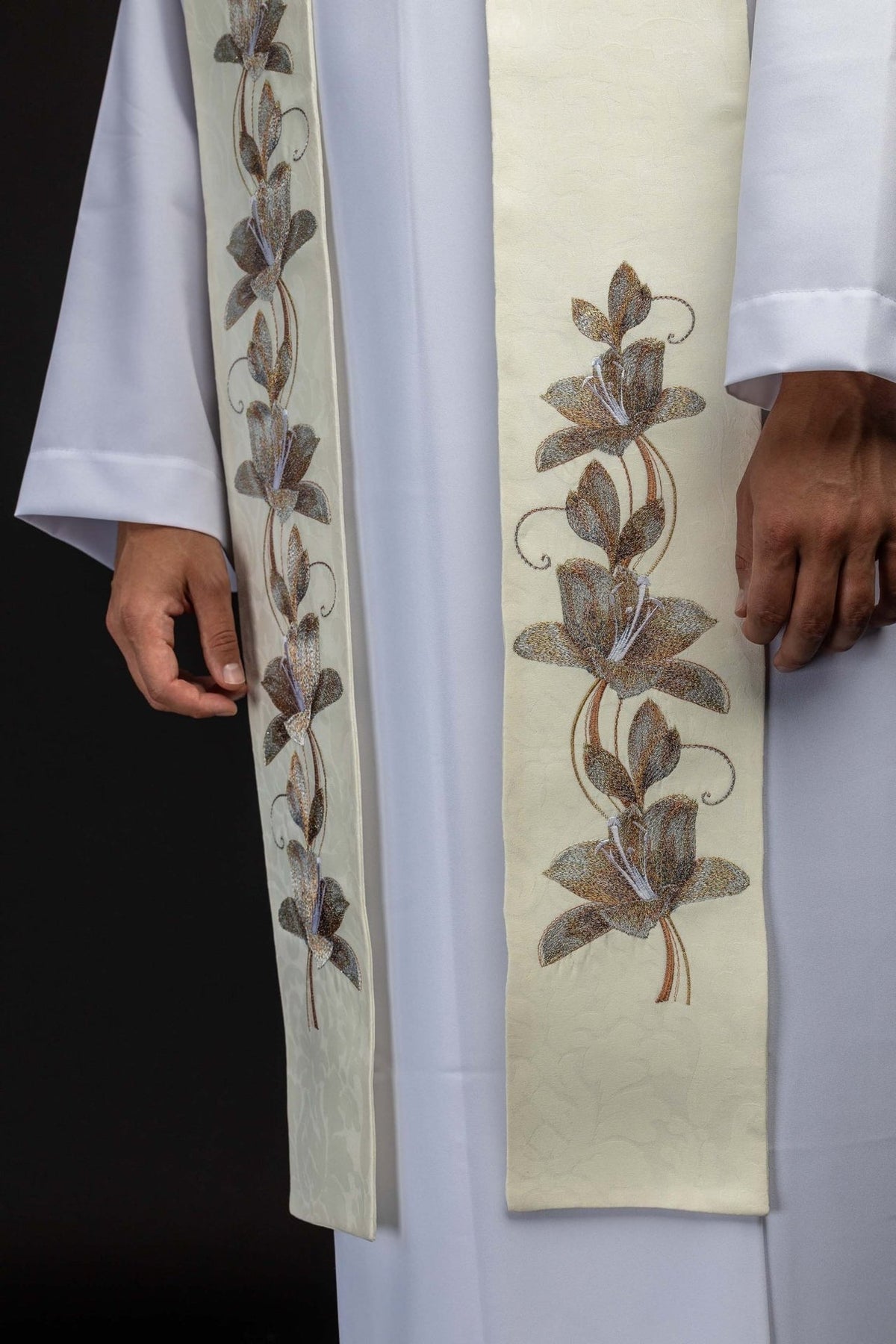 Stole close-up showing repeated brown and gold floral embroidery on ecru fabric