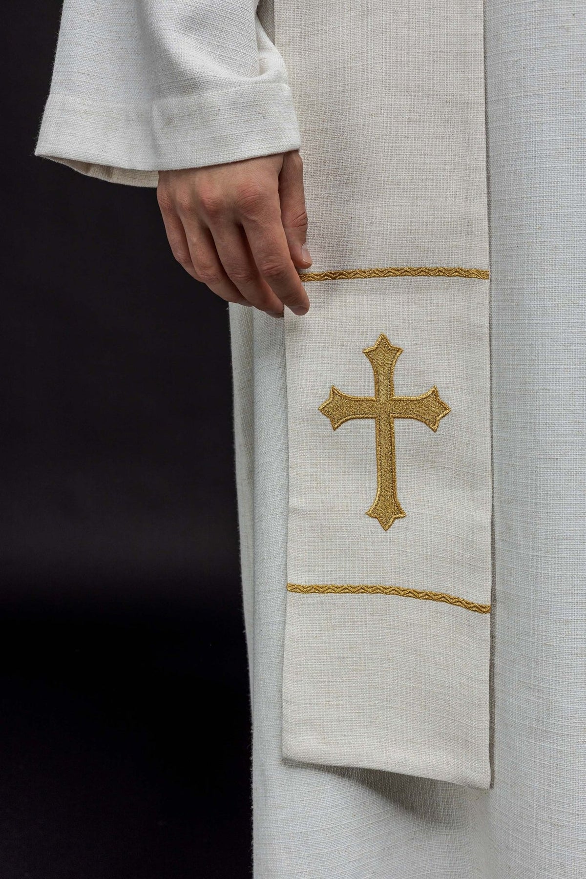 White stole close-up showing a gold embroidered cross and decorative borders