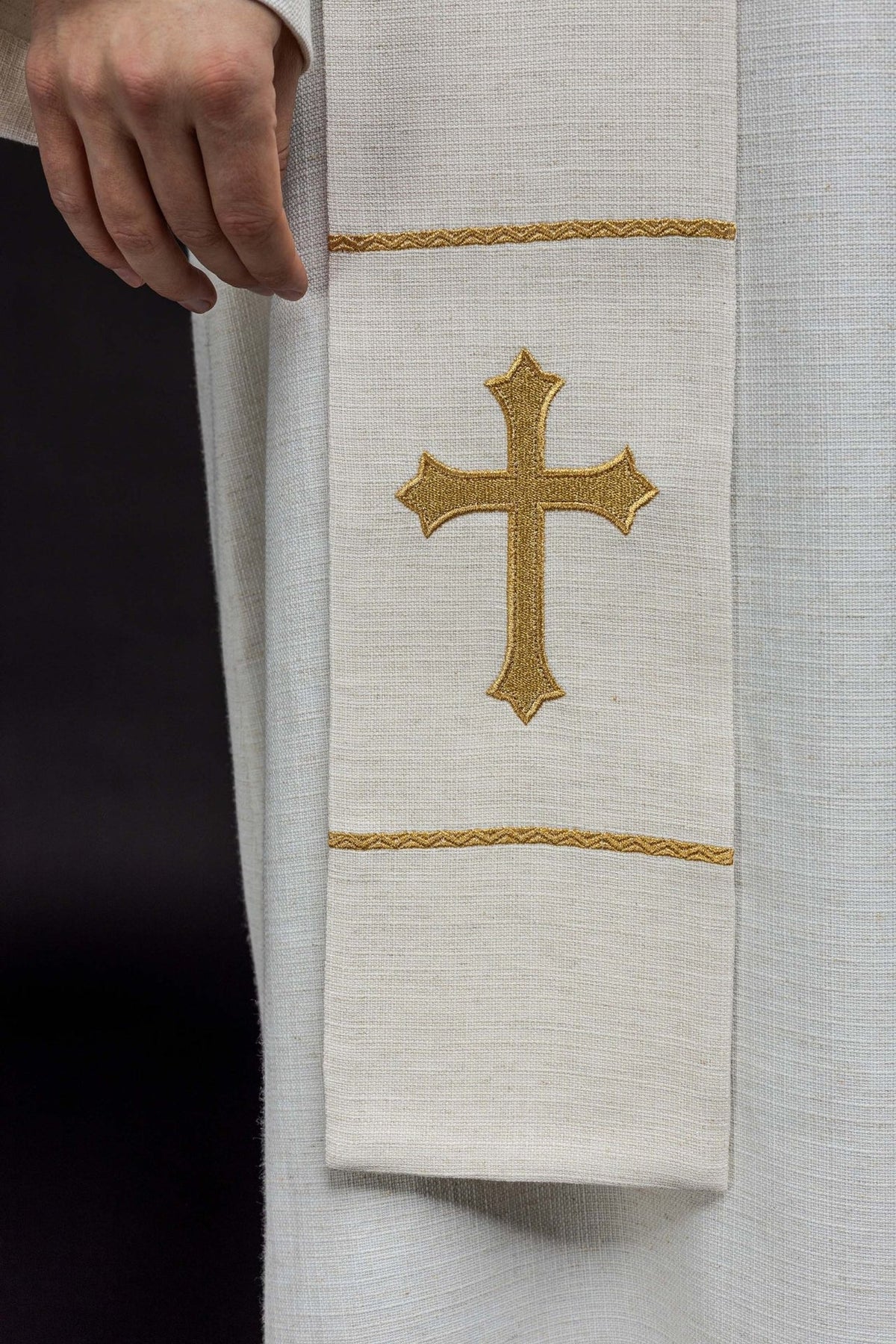 Embroidered stole close-up showing a gold cross and decorative gold bands